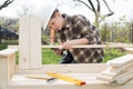 Teen boy in helmet with a screwdriver making a garden bench outdoors.