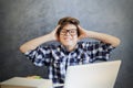 Teen boy holding his head and using laptop Royalty Free Stock Photo