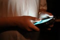 Teen boy holding smart phone in low light