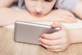 Teen boy lies on carpet and watches video in smartphone. Selective focus on smartphone