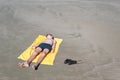 Teen boy lies on yellow towel and sunbathes on the beach. Royalty Free Stock Photo