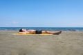 Teen boy lies on yellow towel and sunbathes on the beach.