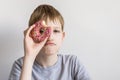 Teen boy looks into bitten donut and funny grimaces