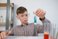 Teen boy is mixing blue color pill in tube doing chemistry experiments.