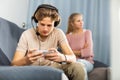 Teen boy playing game on phone against background of frustrated mother Royalty Free Stock Photo