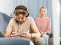 Teen boy playing game on phone against background of frustrated mother Royalty Free Stock Photo