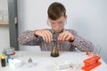 Boy mixing soda, citric acid and liquids in flask doing chemistry gas reaction.
