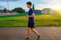 Teen boy running along the stadium track, a soccer field with green grass - concept of sports and health Royalty Free Stock Photo