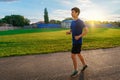 Teen boy running along the stadium track, a soccer field with green grass - concept of sports and health Royalty Free Stock Photo