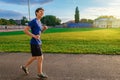 Teen boy running along the stadium track, a soccer field with green grass - concept of sports and health Royalty Free Stock Photo