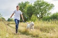 Teen boy running with dog, playing owner and pet in summer meadow