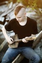 Teen boy with a shovel as a guitar in his hands. Difficult awkward age. Problem teenager in with Mohawk hairstyle