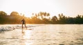 Teen boy silhouette riding a long surfboard. He caught a wave in an Indian ocean bay with magic sunset background. Extreme water Royalty Free Stock Photo