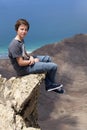 Teen boy sitting on a rock at the coast Royalty Free Stock Photo