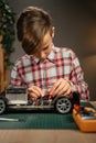 Teen boy sitting at table and soldering remote controlled car. Caucasian child fixing favorite toy by himself at home.