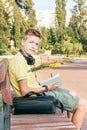 Teen boy is sitting and writing on the bench. Royalty Free Stock Photo