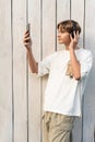 teen boy taking selfie on a white wooden background outdoor, sharing in social media, teen lifestyle, blogging, teenager