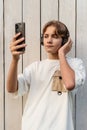 teen boy taking selfie on a white wooden background outdoor, sharing in social media, teen lifestyle, blogging, teenager