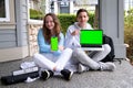 teen boy and teenage girl sitting outdoors with folders backpack holding laptop and phone green screen chroma key ad Royalty Free Stock Photo