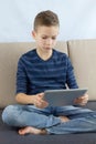 Teen boy using touchscreen tablet. Young boy playing game or checking social media on tablet at home. Internet online education