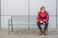 Teen boy waiting and sitting on metal bench outdoor in town