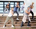 Teen boys and girls dancing modern choreography on city street