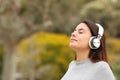 Teen breathing with headphones meditating in a park