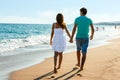 Teen couple walking away on beach.