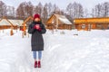 Teen cute girl in black down jacket, blue cropped jeans, burgundy hat, boots and fingerless gloves standing outdoor against winter Royalty Free Stock Photo