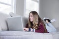 Teen female student web conferencing calling on the couch doing school work from home