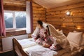 Teen friends in same Christmas pajamas relaxing in bed inside cozy log cabin with winter view Royalty Free Stock Photo