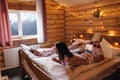 Teen friends in same Christmas pajamas relaxing in bed inside cozy log cabin with winter view Royalty Free Stock Photo
