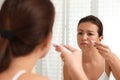 Teen girl with acne problem applying cream near mirror Royalty Free Stock Photo