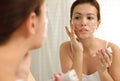 Teen girl with acne problem applying cream near mirror Royalty Free Stock Photo