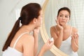 Teen girl with acne problem applying cream near mirror Royalty Free Stock Photo