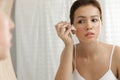 Teen girl with acne problem applying cream near mirror Royalty Free Stock Photo