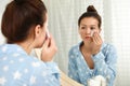 Teen girl with acne problem cleaning face near mirror in bathroom Royalty Free Stock Photo