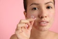 Teen girl applying acne healing patch on pink background