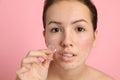 Teen girl applying acne healing patch on pink background