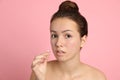 Teen girl applying acne healing patch on pink background