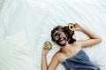 Teen girl applying black clay facial mask with avocado