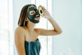 Teen girl applying black clay facial mask with avocado Royalty Free Stock Photo