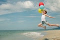 Teen girl with balloons jumping on the beach at the day time Royalty Free Stock Photo