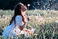 Teen girl blowing seeds from a flower dandelion in spring park Royalty Free Stock Photo