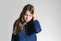 A teen girl in a blue dress with a headache holding her head with one arm not looking at a camera Royalty Free Stock Photo