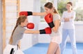 Teen girl in boxing gloves practicing punches in sparring during self-defense course