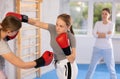 Teen girl in boxing gloves practicing punches in sparring during self-defense course