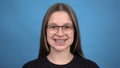 Teen girl with braces smiling on a blue background. Girl with colored braces.