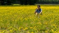 Teen girl with braids sitting in large field with yellow flowers