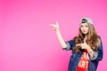 Teen girl in cap pointing at side and showing by fingers.